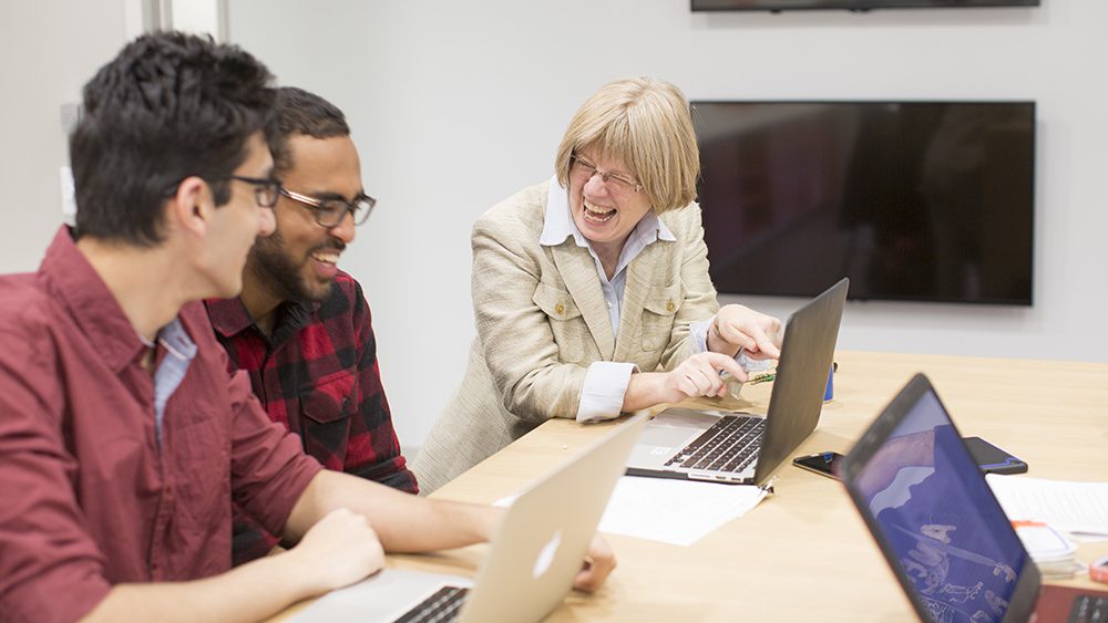 Professor laughing with two male students