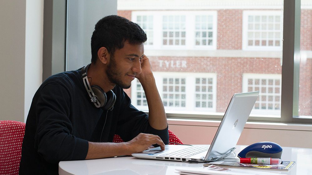 Male student looking at computer with headphones on