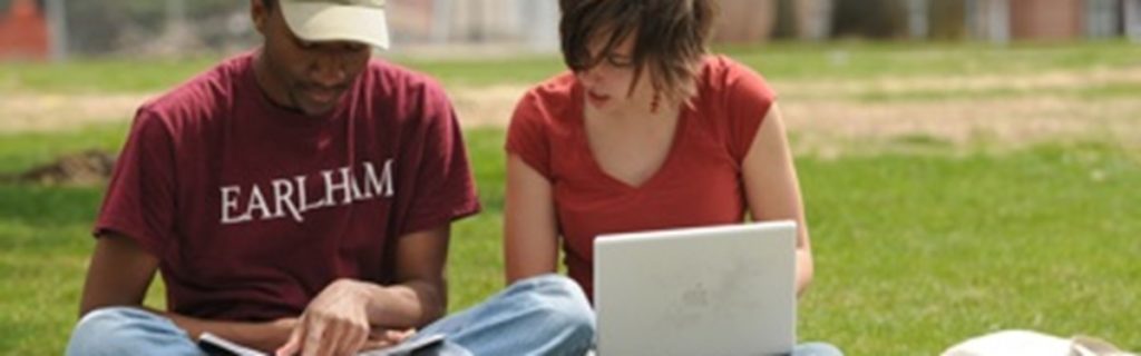 Two Earlham students studying on the campus lawn 