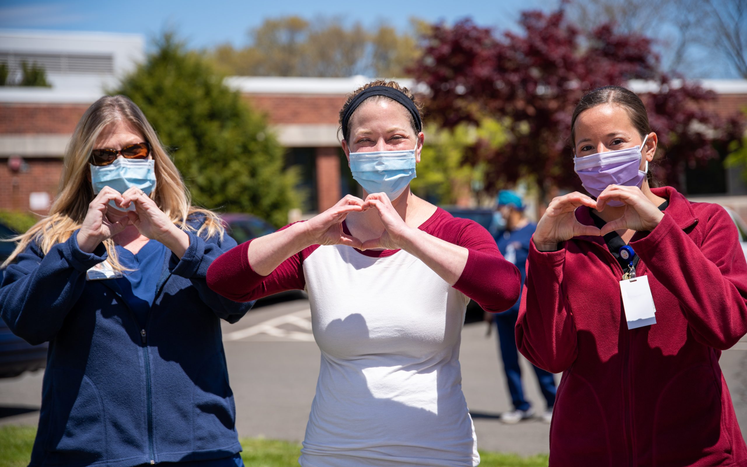 Women with masks on making hearts with their hands