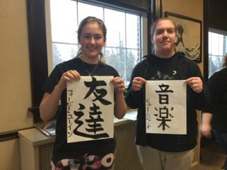 Two language and culture students holding a Japanese writing banner