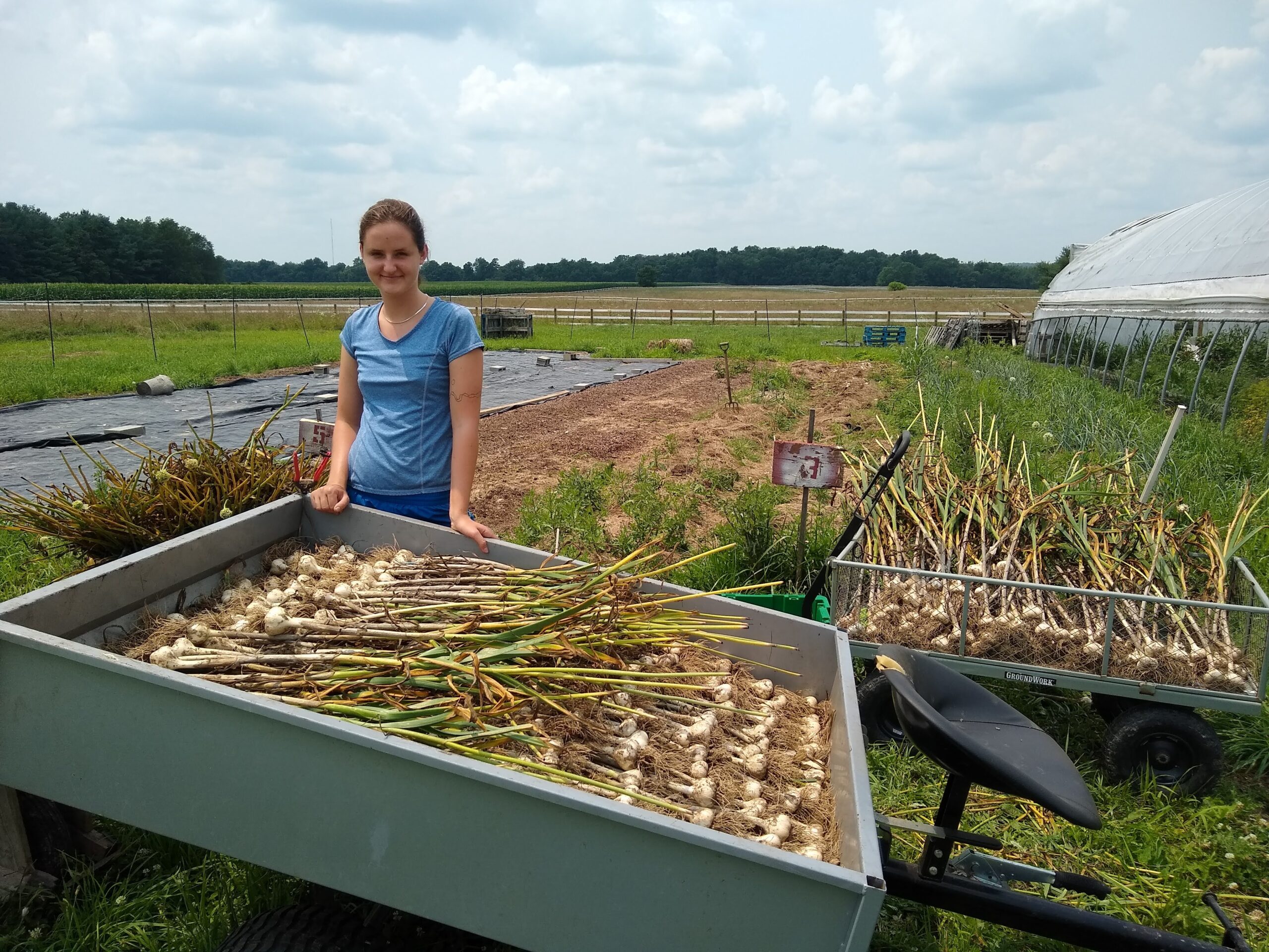 A student standing with her root veggie harvest