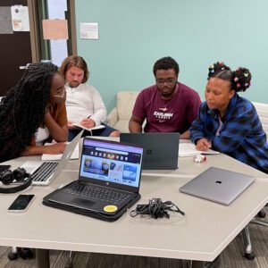 Earlham students gathered around a collaboration station with their laptops