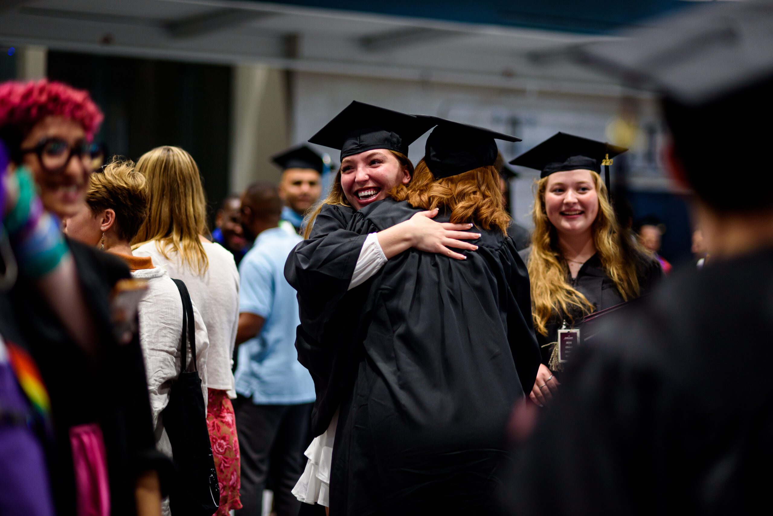 Earlham graduates embracing inside the Druley Performance Gymnasium at the Athletics and Wellness Center.