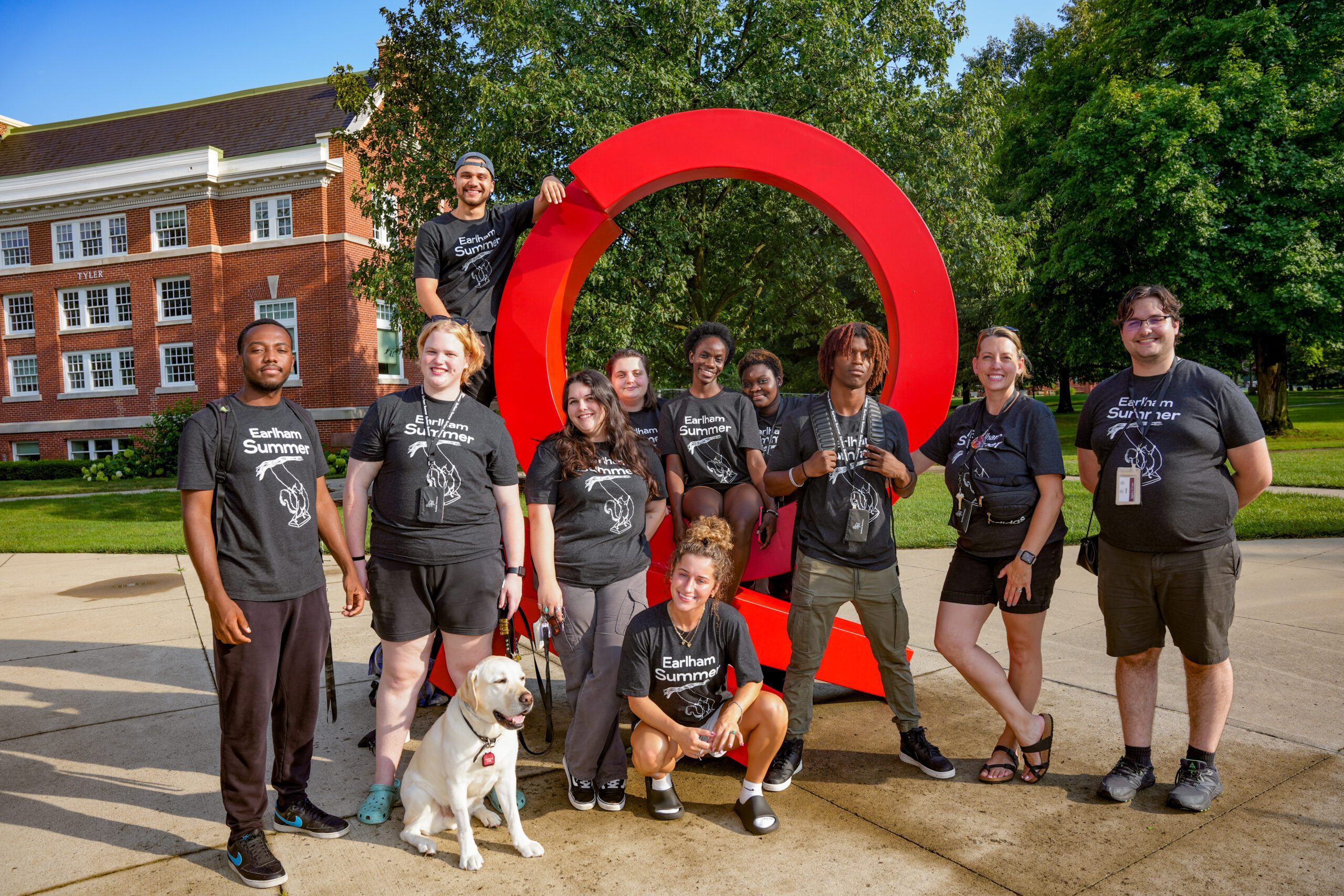 Earlham Summer 2024 group leaders posing in front of a sculpture on campus