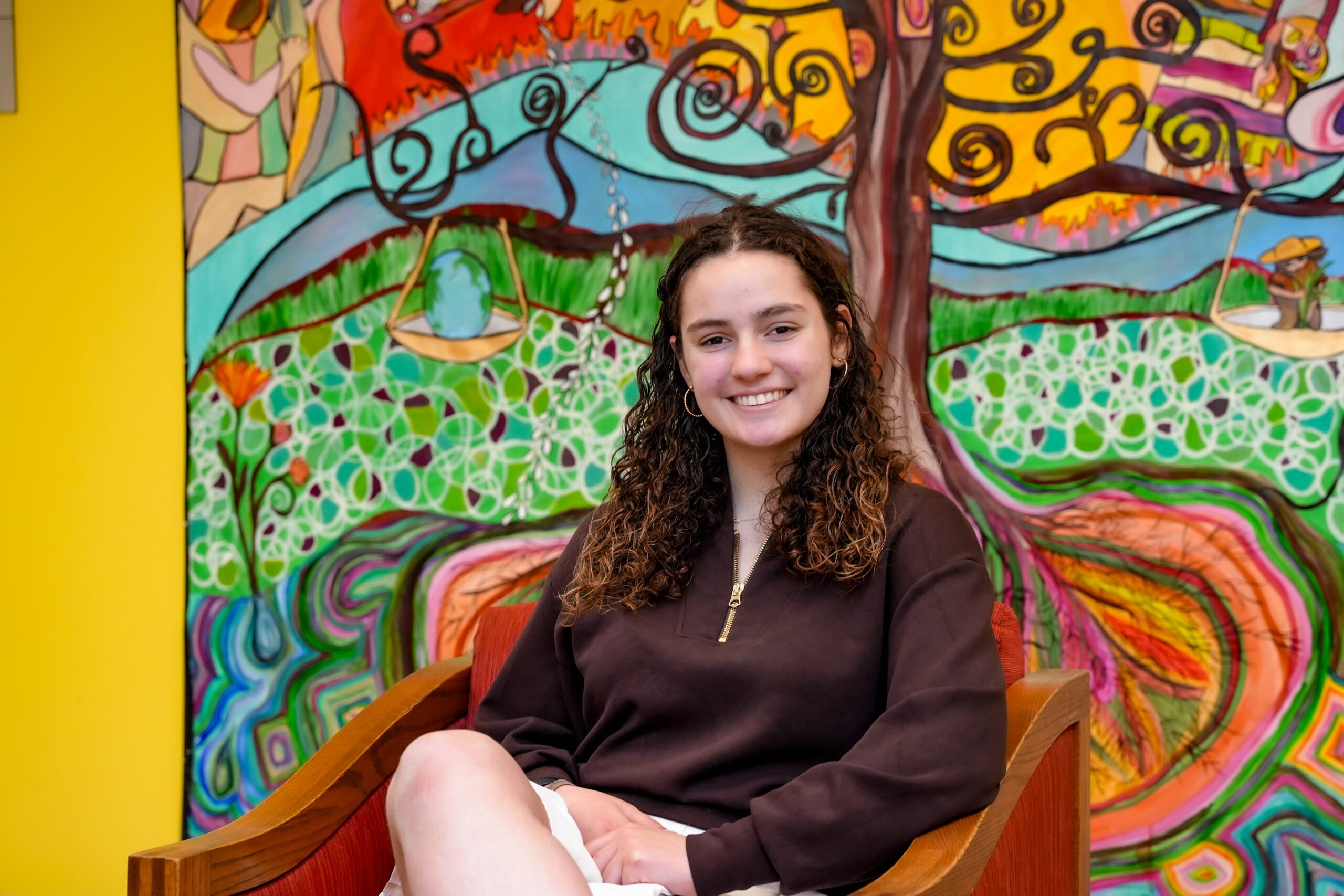 Sydney Schmitt sitting in front of a colorful mural