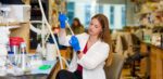 Sarah Dickman wears blue gloves while she holds scientific instruments at a lab at Cincinnati Children's Hospital.