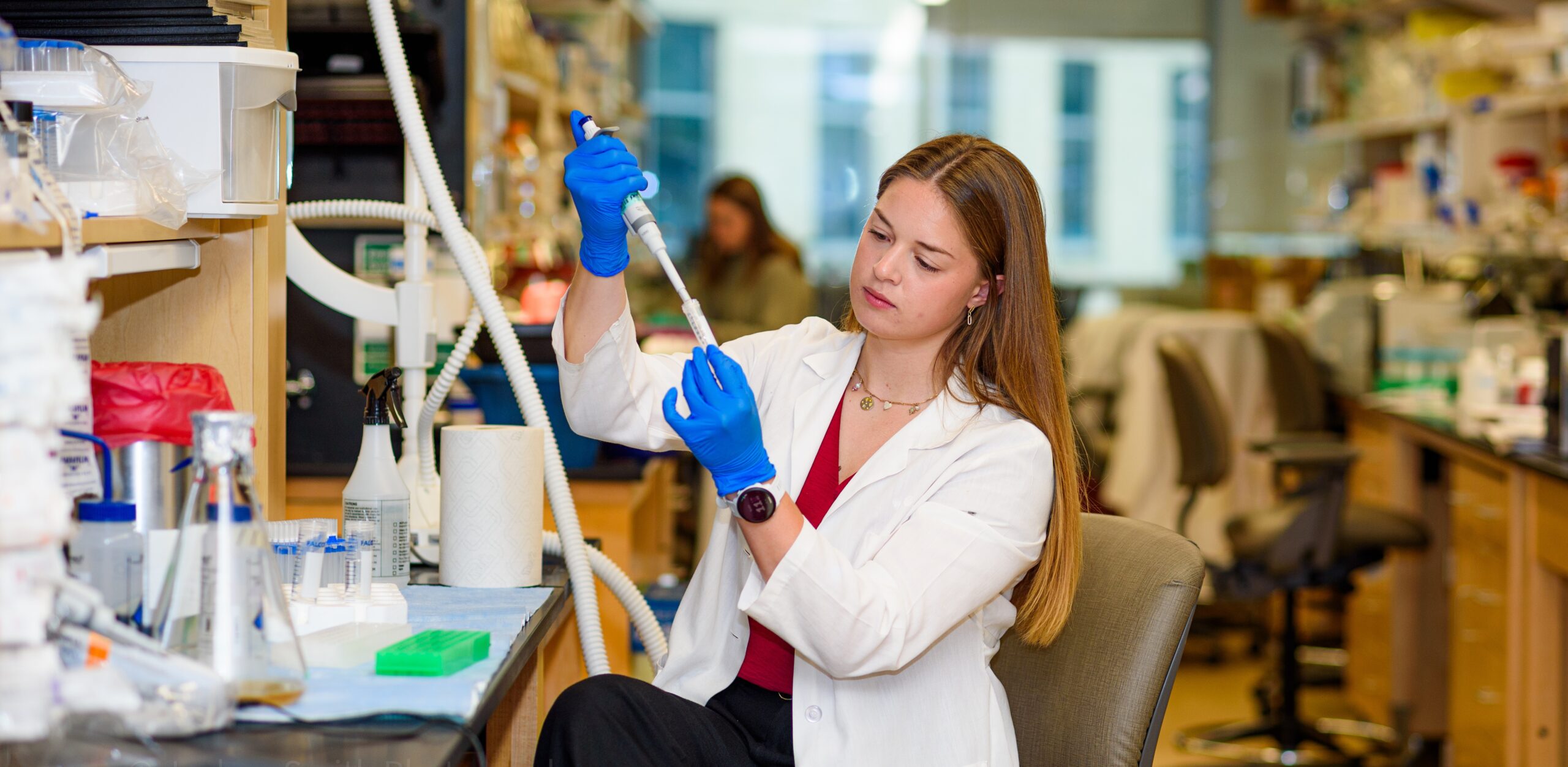 Sarah Dickman wears blue gloves while she holds scientific instruments at a lab at Cincinnati Children's Hospital.