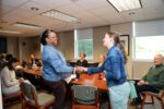 Bonita Washington-Lacey is pictured left shaking hands with Lynette Davis of the Wayne County Area Chamber of Commerce after a surprise announcement in a conference room about the Educator of the Year Award.