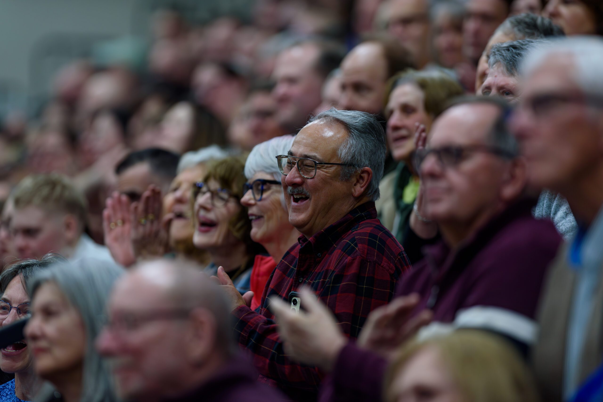 A close up image of audience members smiling and clapping