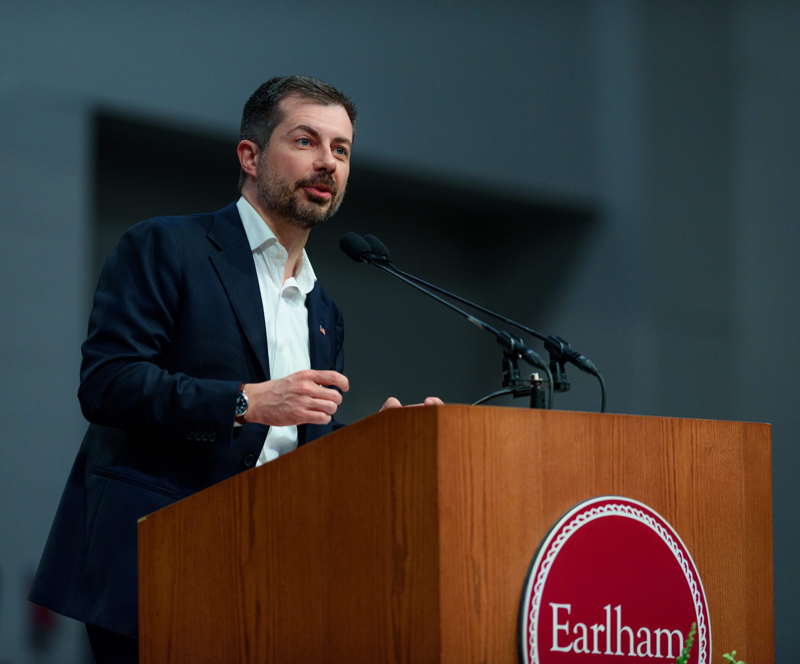 Pete Buttigieg stands behind a podium with Earlham College's logo on the front