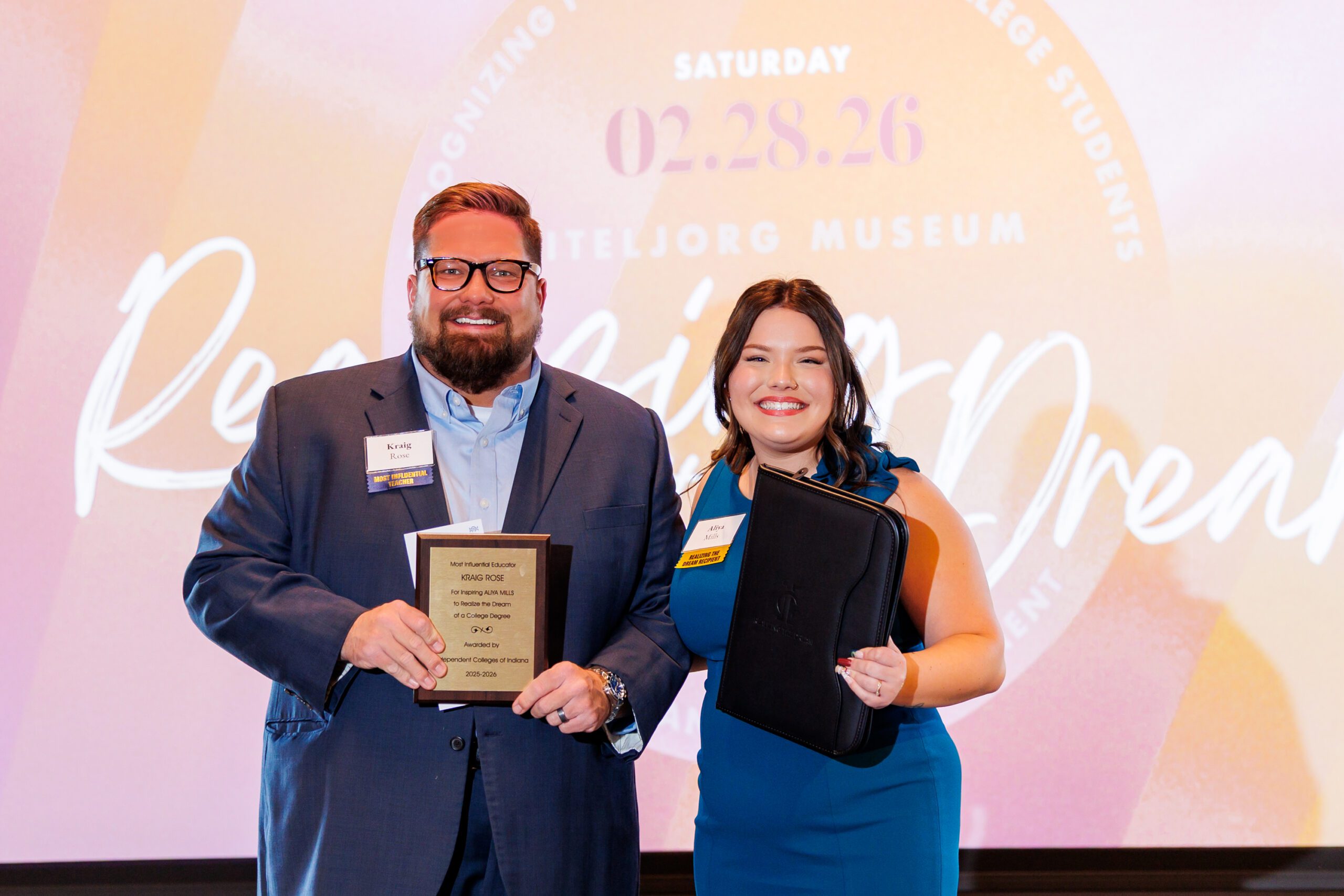 Teacher Kraig Rose at left and Earlham College student Aliya Mills at right pose with plaques at a ceremony