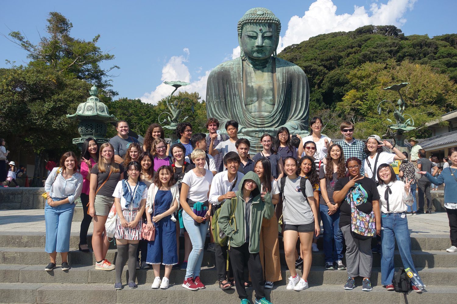A large group of students pose in front of a statue depicting the Great Buddha of Kamakura