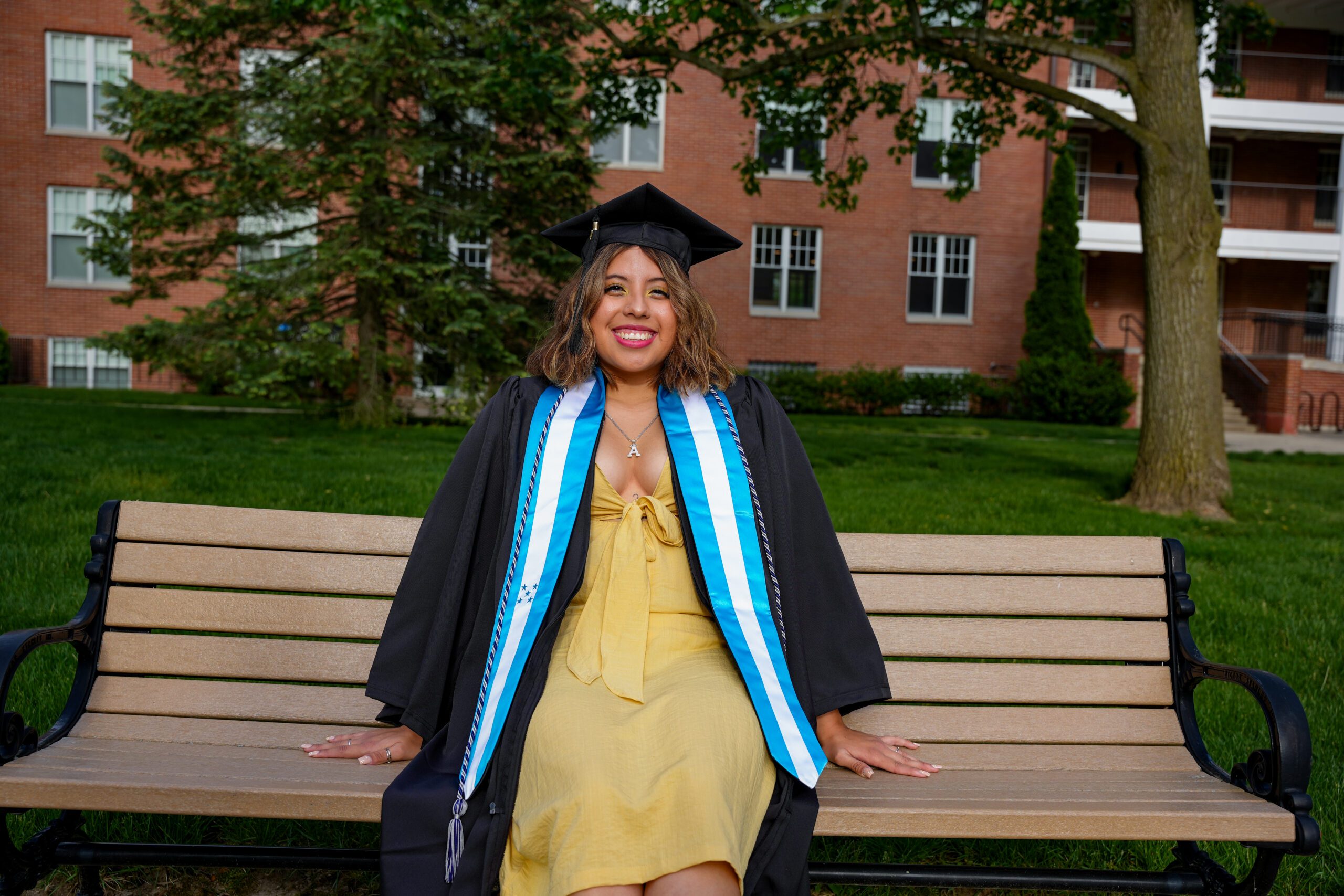 Rose Leon-Alvarado sits on a bench with her commencement regalia on