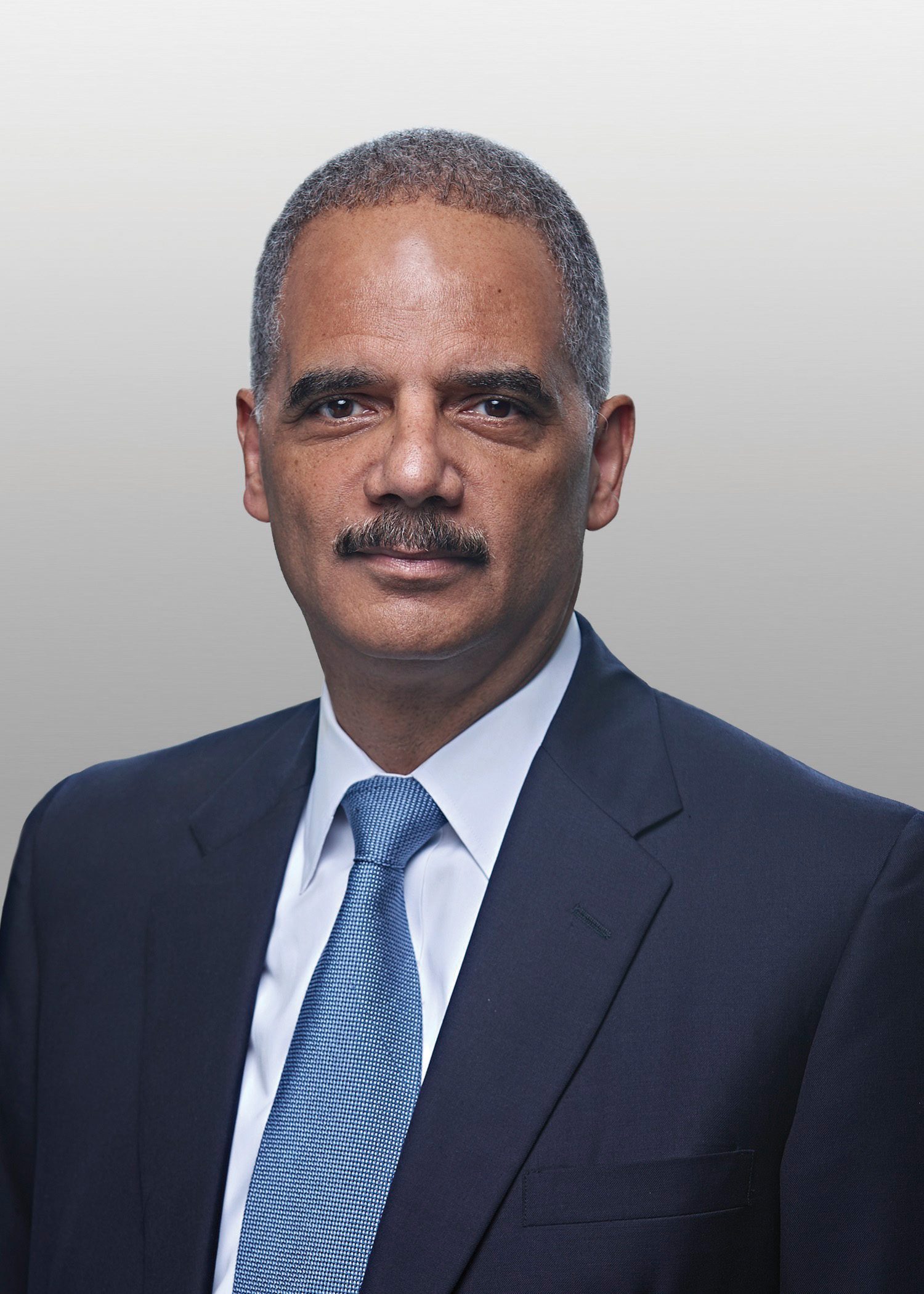 Eric Holder posing for a headshot wearing a crisp suit.