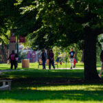 Seven students walk across a tree-lined path on Earlham College's campus