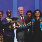 Four Earlham College students surround former U.S. President Bill Clinton after receiving the Hult Prize