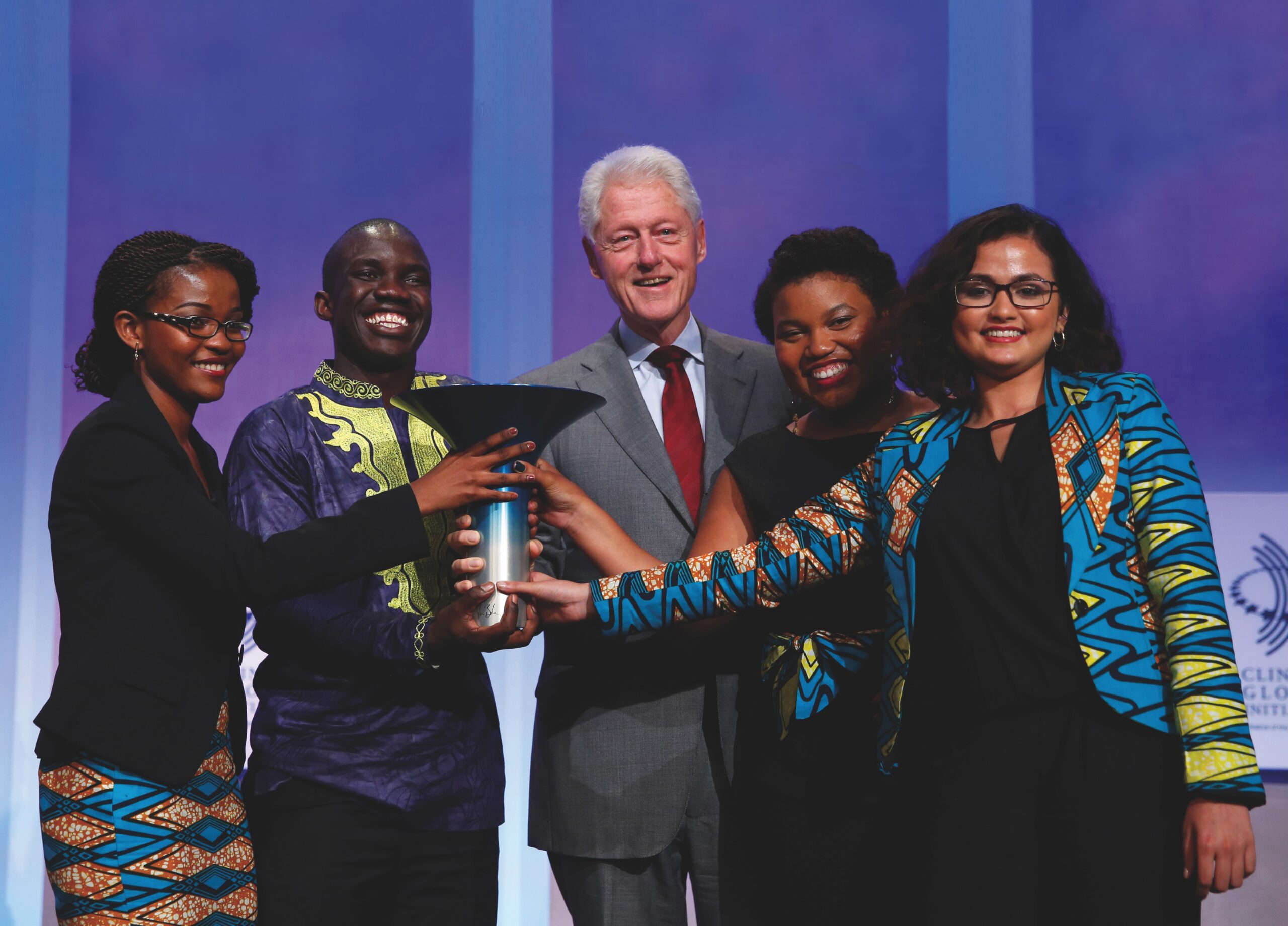 Four Earlham College students surround former U.S. President Bill Clinton after receiving the Hult Prize